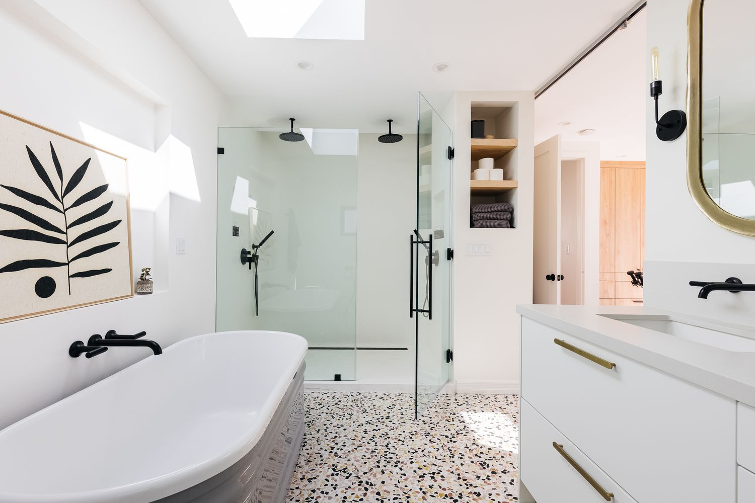 Modern bathroom with terrazzo floor, freestanding tub, and glass shower.