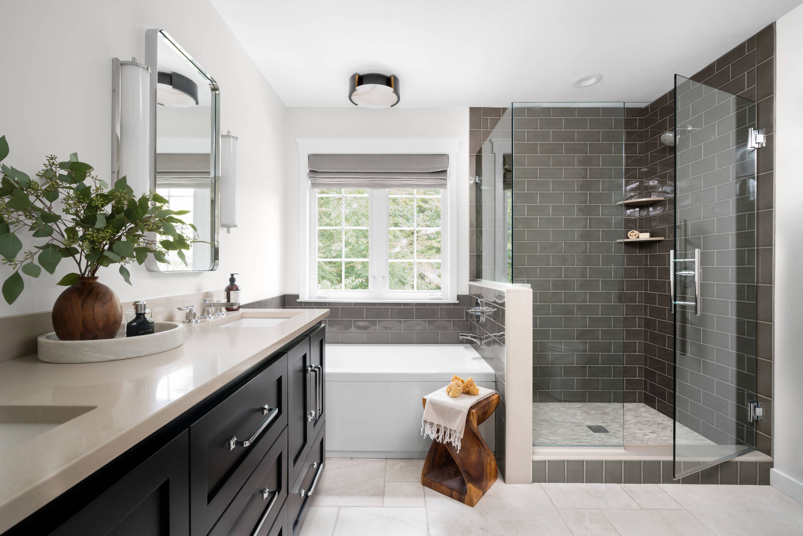 Modern bathroom with dark vanity, glass shower, and built-in bathtub.