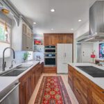Modern galley kitchen with wood cabinets and white countertops.