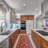 Modern galley kitchen with wood cabinets and white countertops.