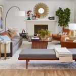 Stylish living room with a sunburst mirror, fireplace, and modern furniture.