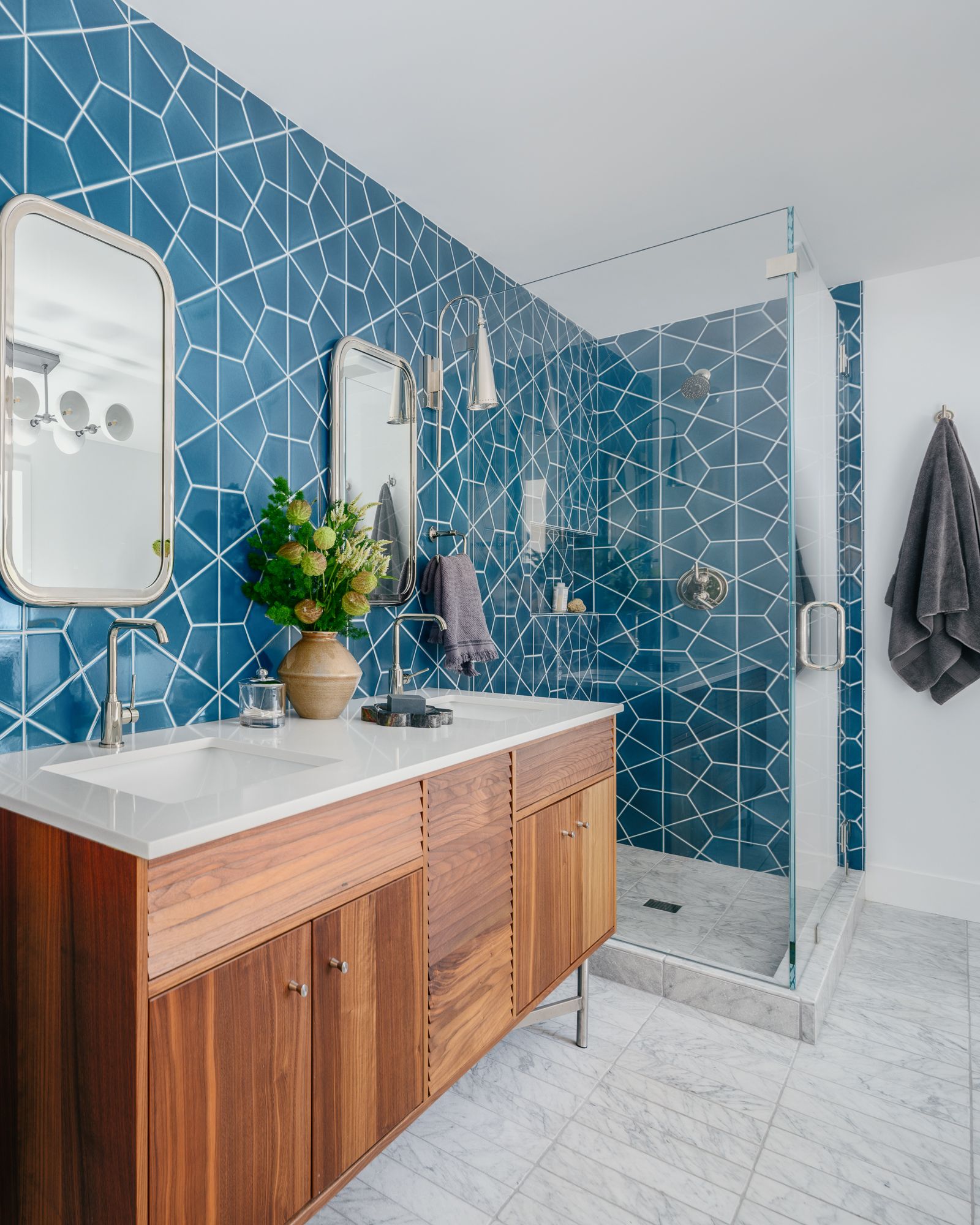 Modern bathroom with bold blue geometric tile wall and glass shower