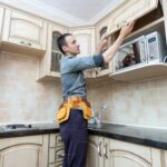 Man installing or adjusting a kitchen cabinet door in a modern kitchen.