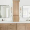 Double vanity bathroom with light wood cabinets, center tower, and modern square mirrors