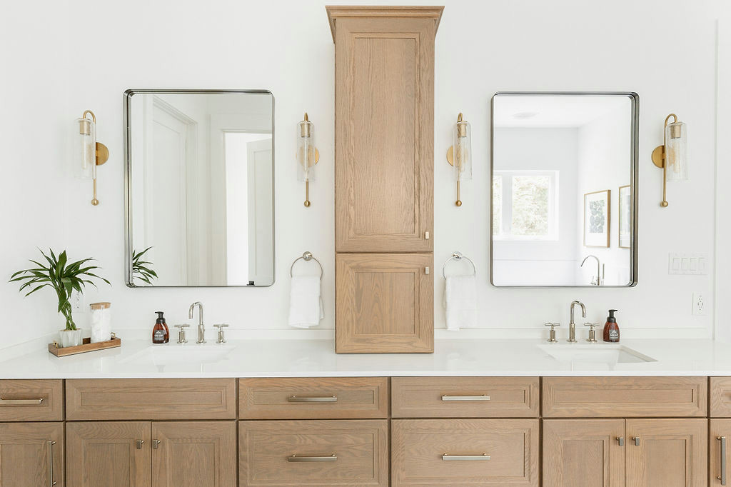 Double vanity bathroom with light wood cabinets, center tower, and modern square mirrors