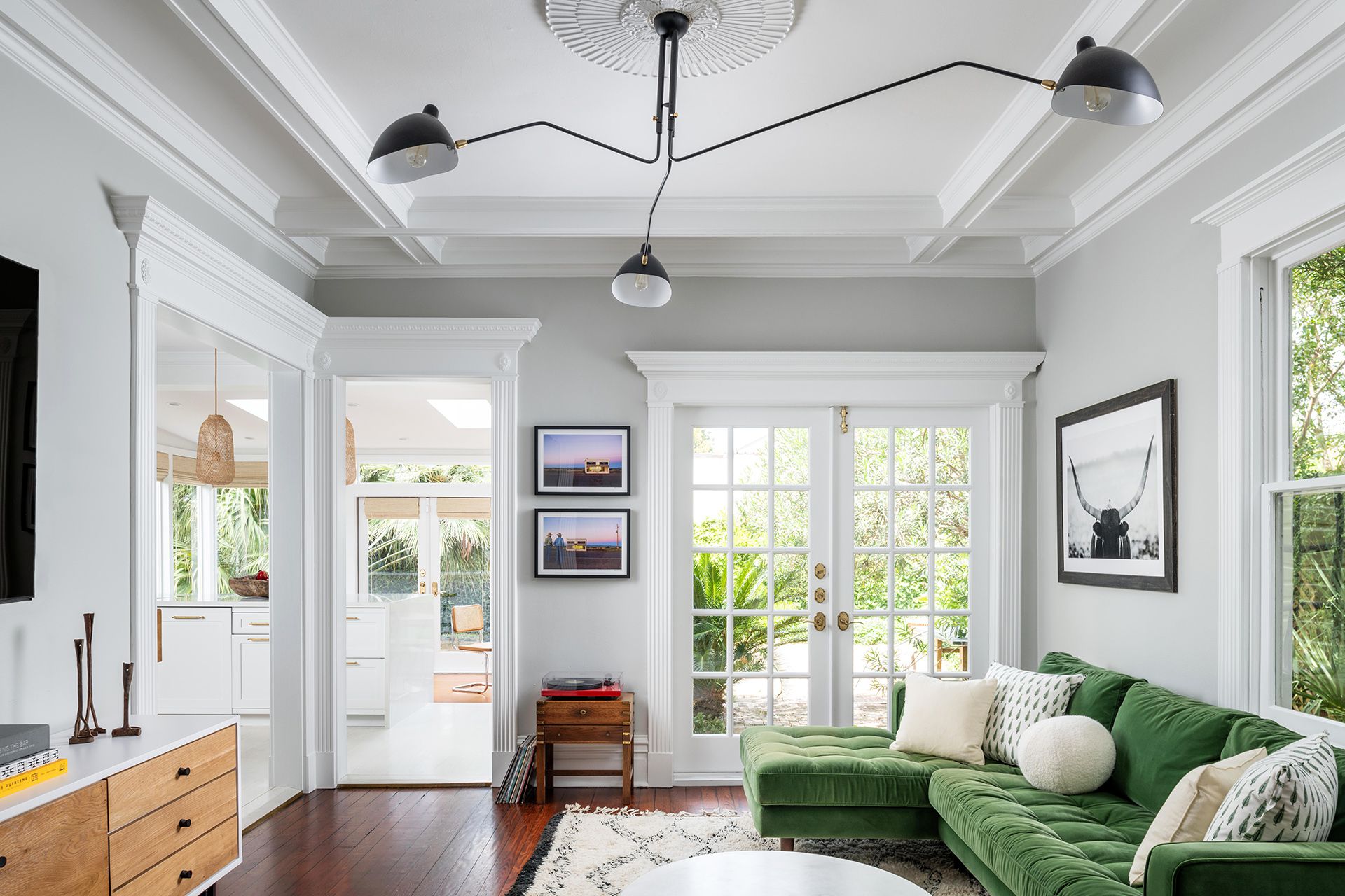 Modern living room with green velvet sofa, white trim, and glass French doors.