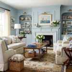 Cozy living room with light blue built-in shelves, neutral sofas, nautical-themed decor, and a white fireplace.