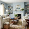 Cozy living room with light blue built-in shelves, neutral sofas, nautical-themed decor, and a white fireplace.