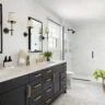 Contemporary bathroom with black vanity, gold fixtures, and glass-enclosed shower.