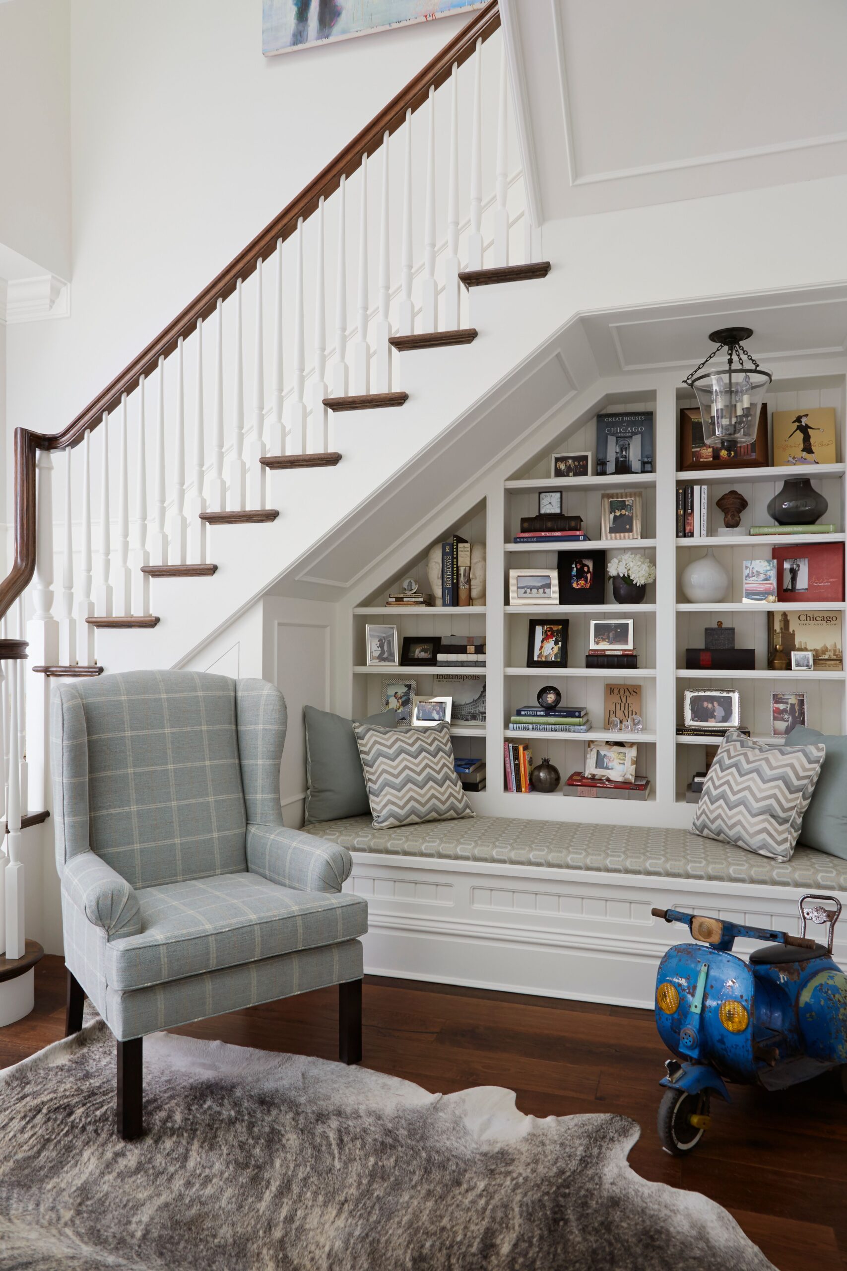 Cozy under-stair reading nook with built-in bookshelf, bench seating, and plaid armchair