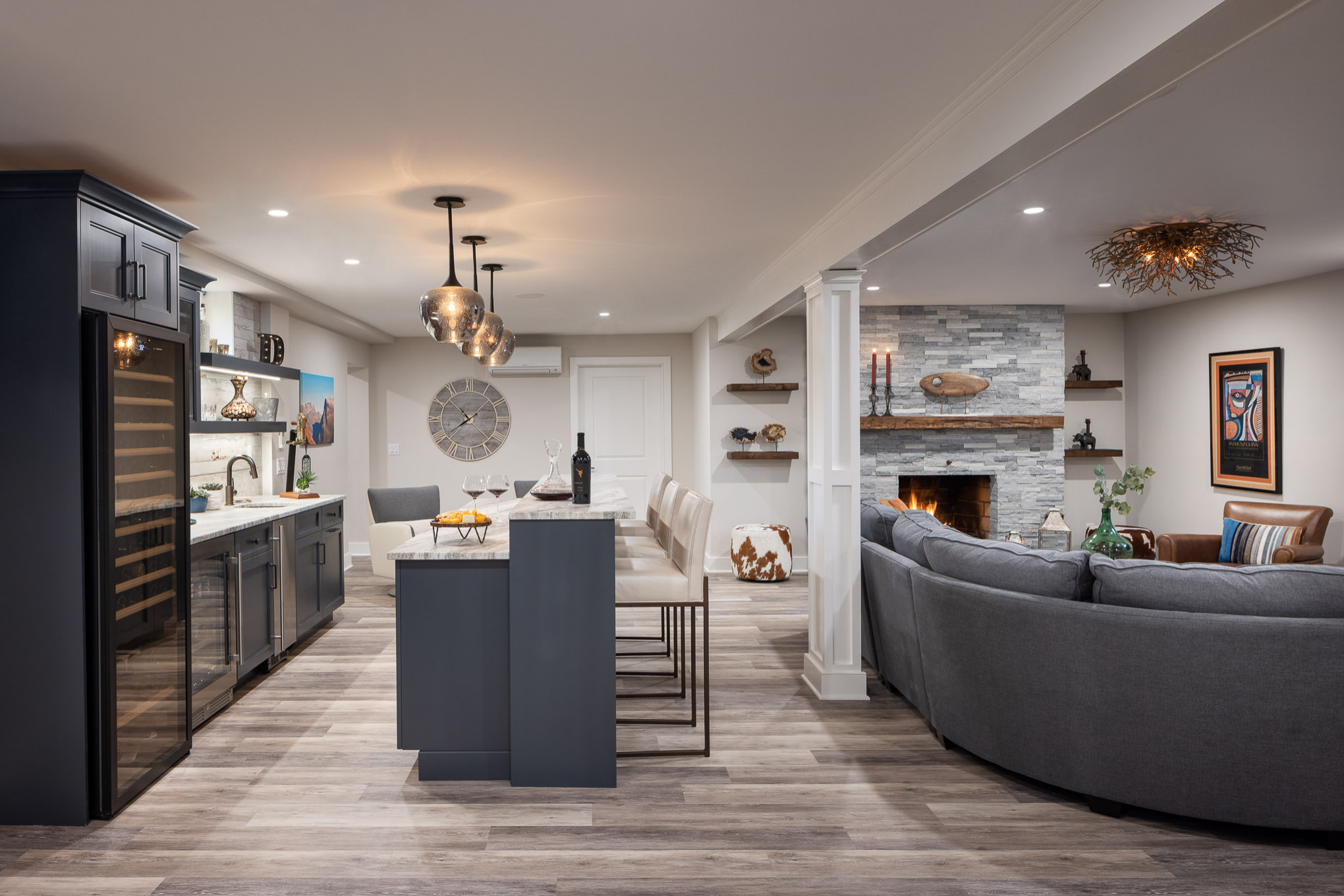 Modern basement with bar area, wine fridge, and cozy living space with fireplace.
