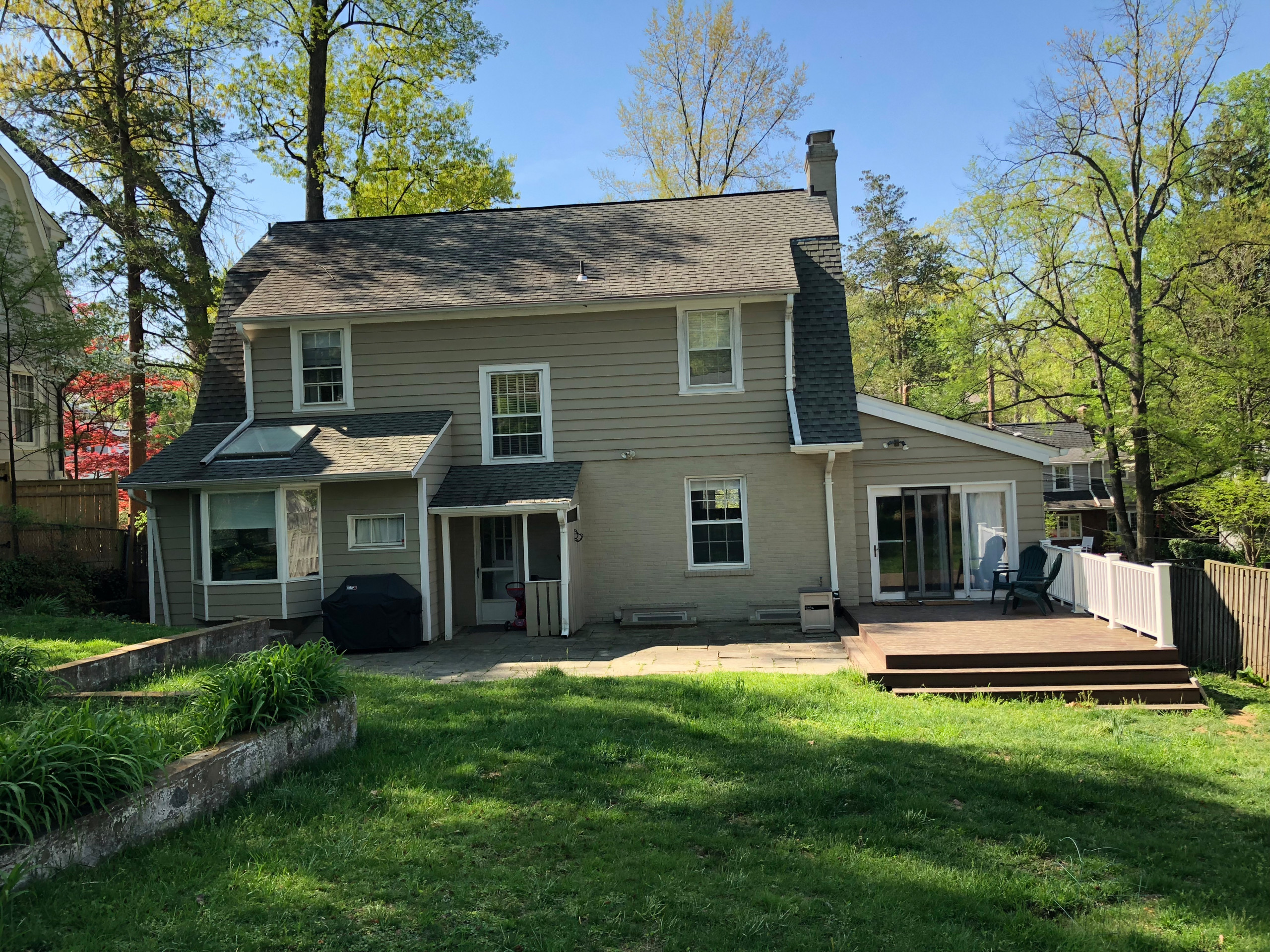 Two-story suburban home with beige siding, back patio, and fenced yard.