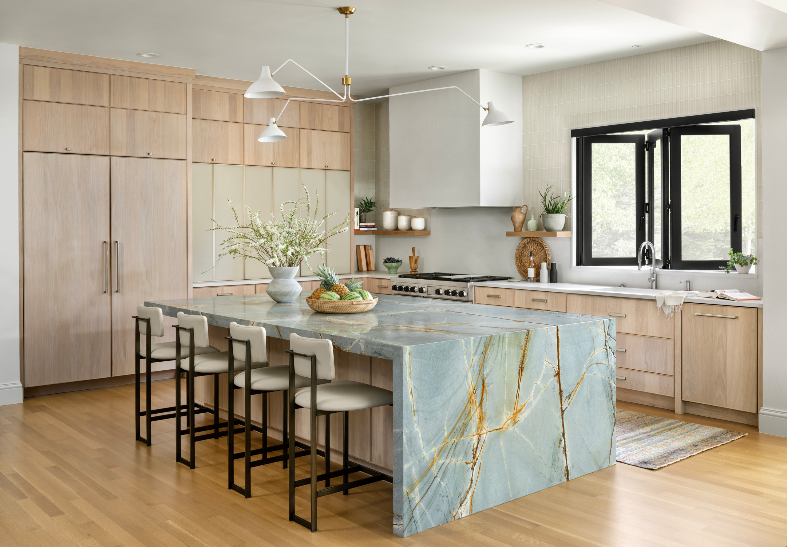 Modern kitchen with light wood cabinets and a large aqua-blue stone island with golden veining.