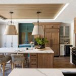 Contemporary kitchen with wood accents, a central island, and mixed cabinet finishes including teal, white, and natural wood tones.