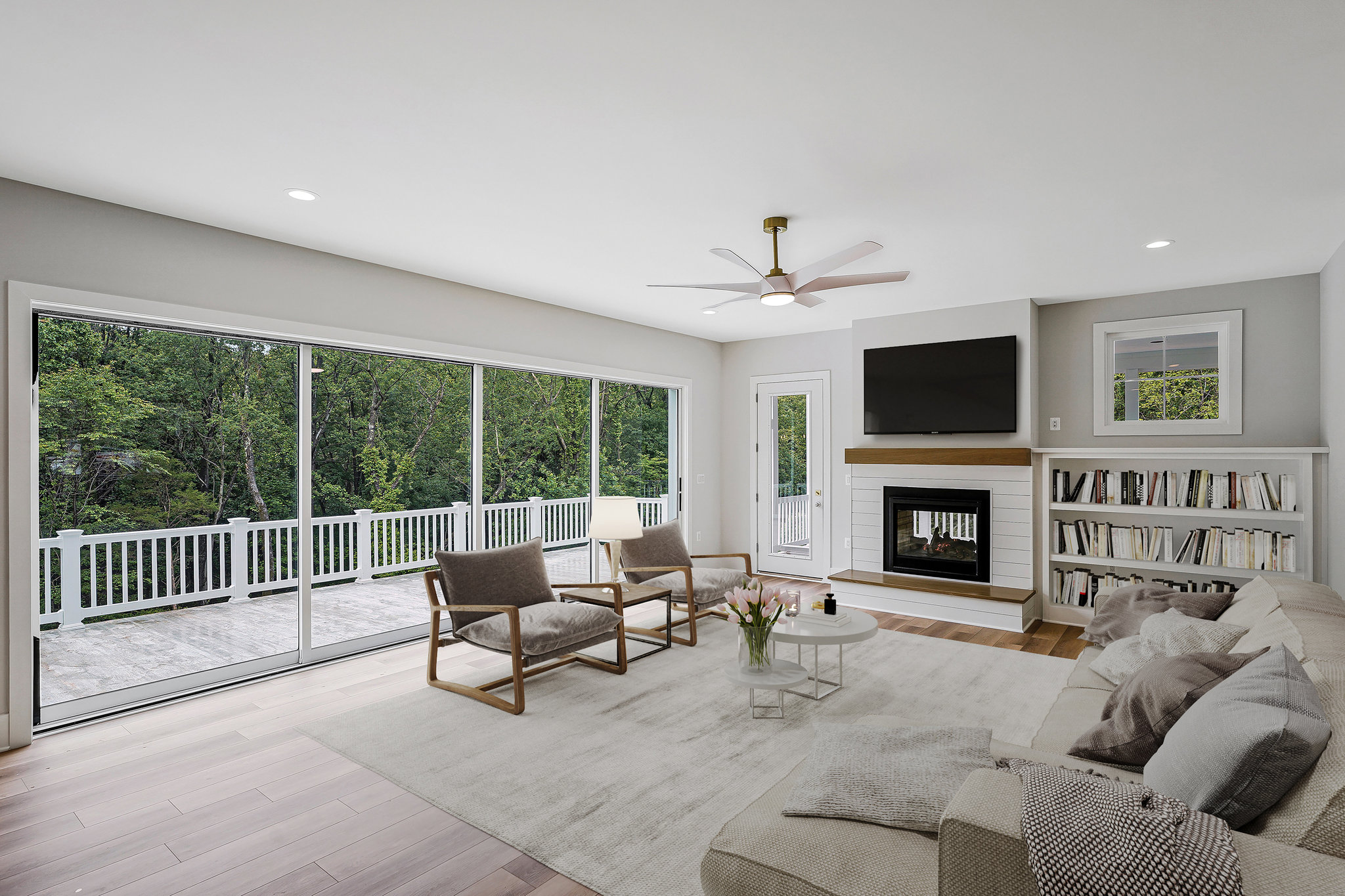 Modern living room with large sliding glass doors, neutral furnishings, built-in bookshelf, and fireplace under wall-mounted TV.