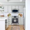 Bright white kitchen with stainless steel appliances and herringbone backsplash