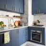 Contemporary kitchen with navy blue cabinets, marble backsplash, and gold hardware
