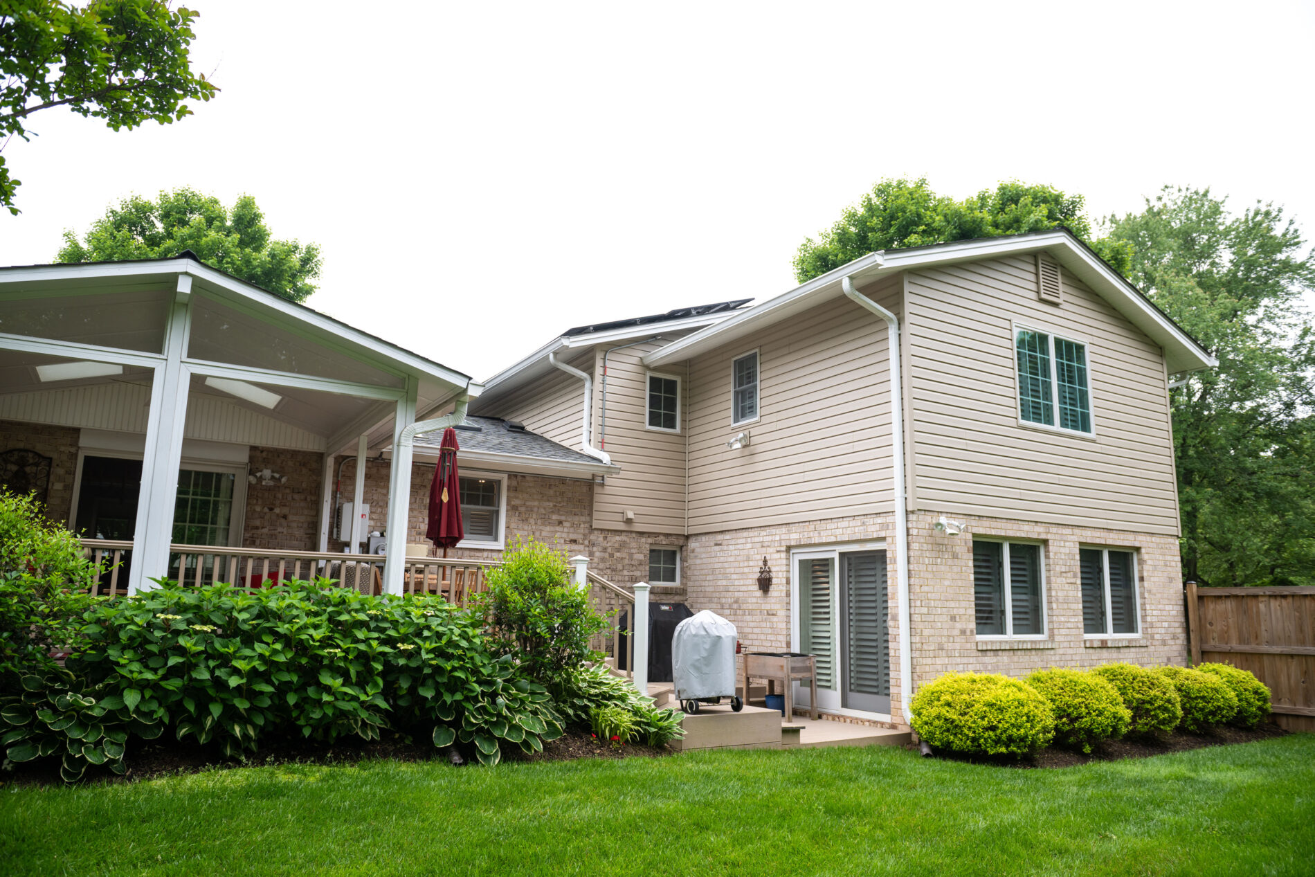 Two-story suburban home with brick and siding exterior, covered patio, and landscaped backyard.