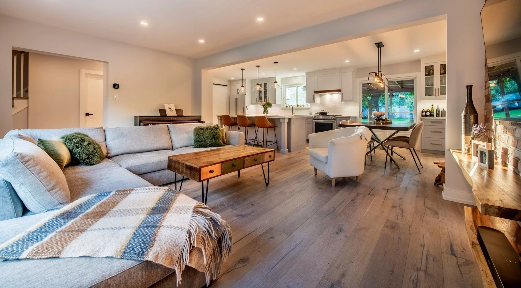 Open-concept living and kitchen space with wood flooring, modern furniture, and warm lighting.