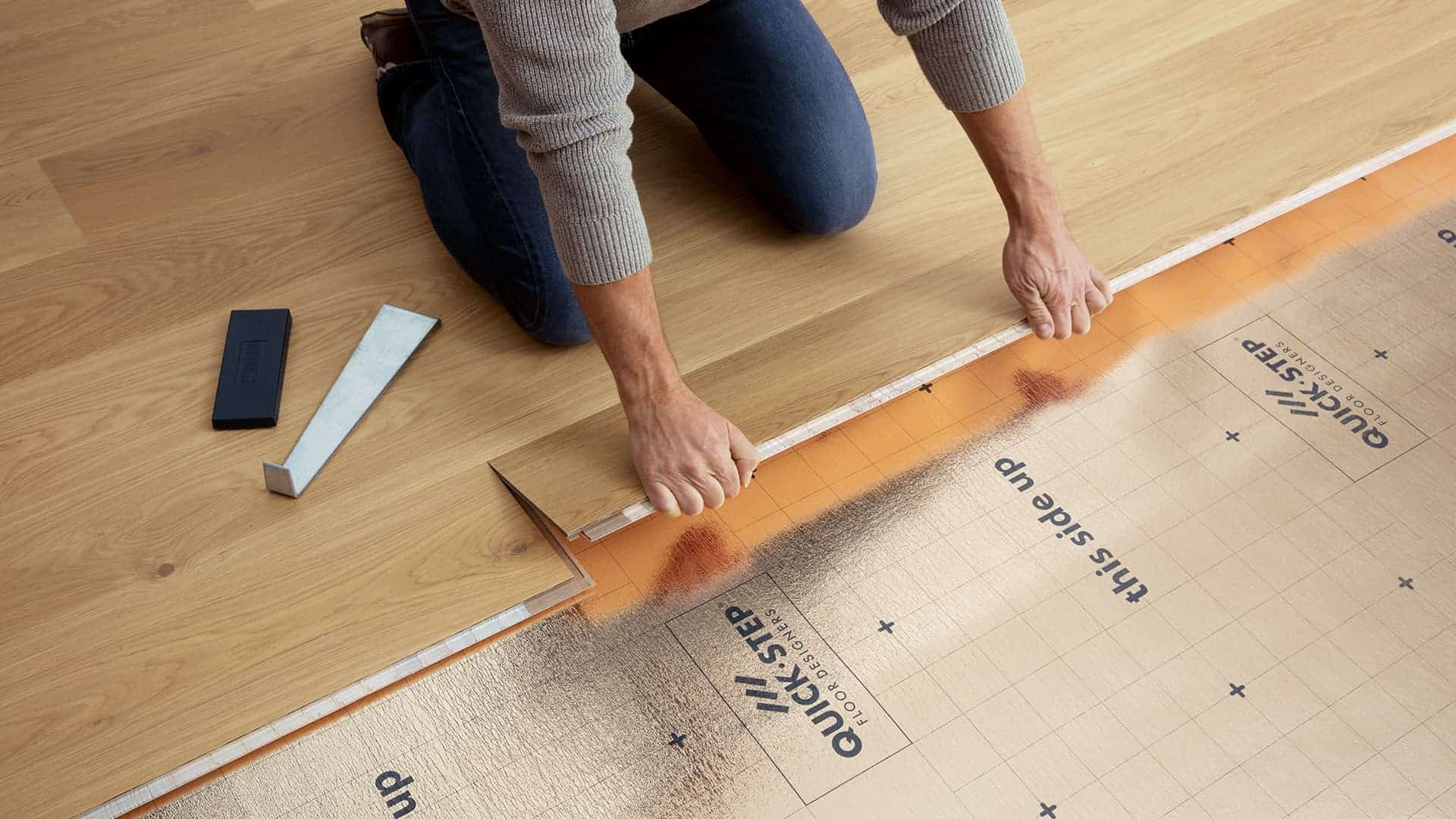 Person installing hardwood flooring over Quick-Step underlayment.