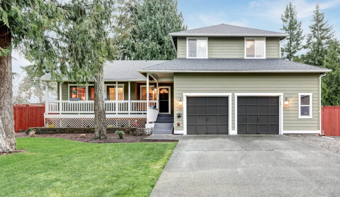 Two-story suburban home with green siding, black garage doors, and front porch.