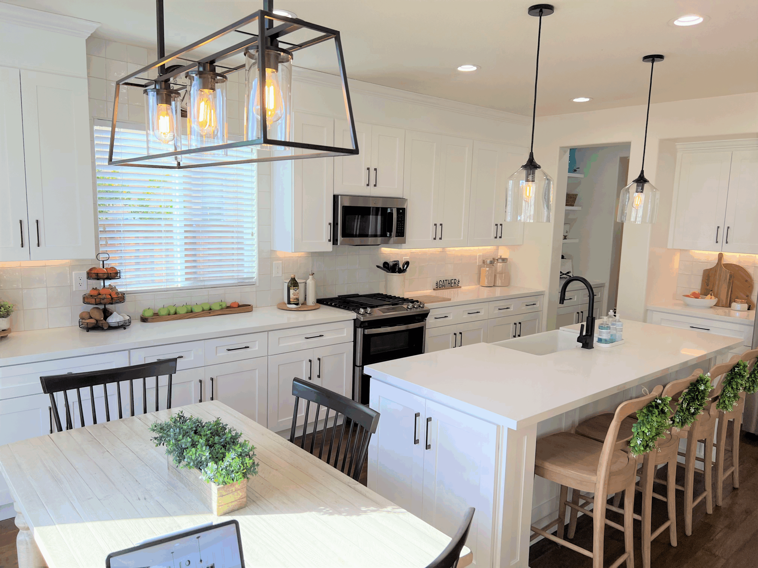 Farmhouse-style kitchen with white shaker cabinets, island seating, pendant lighting, and rustic decor