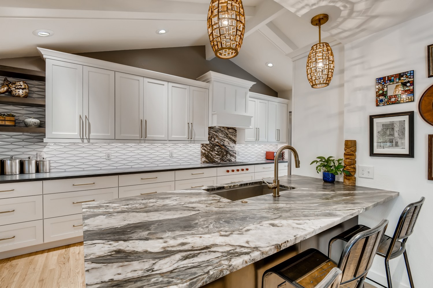 Elegant kitchen with dramatic veined marble countertop, white shaker cabinets, and woven pendant lights