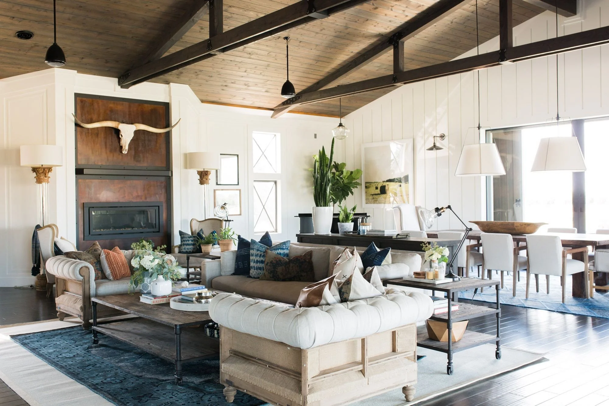 Rustic chic living and dining space with vaulted wood ceiling, eclectic furnishings, and mounted longhorn decor.
