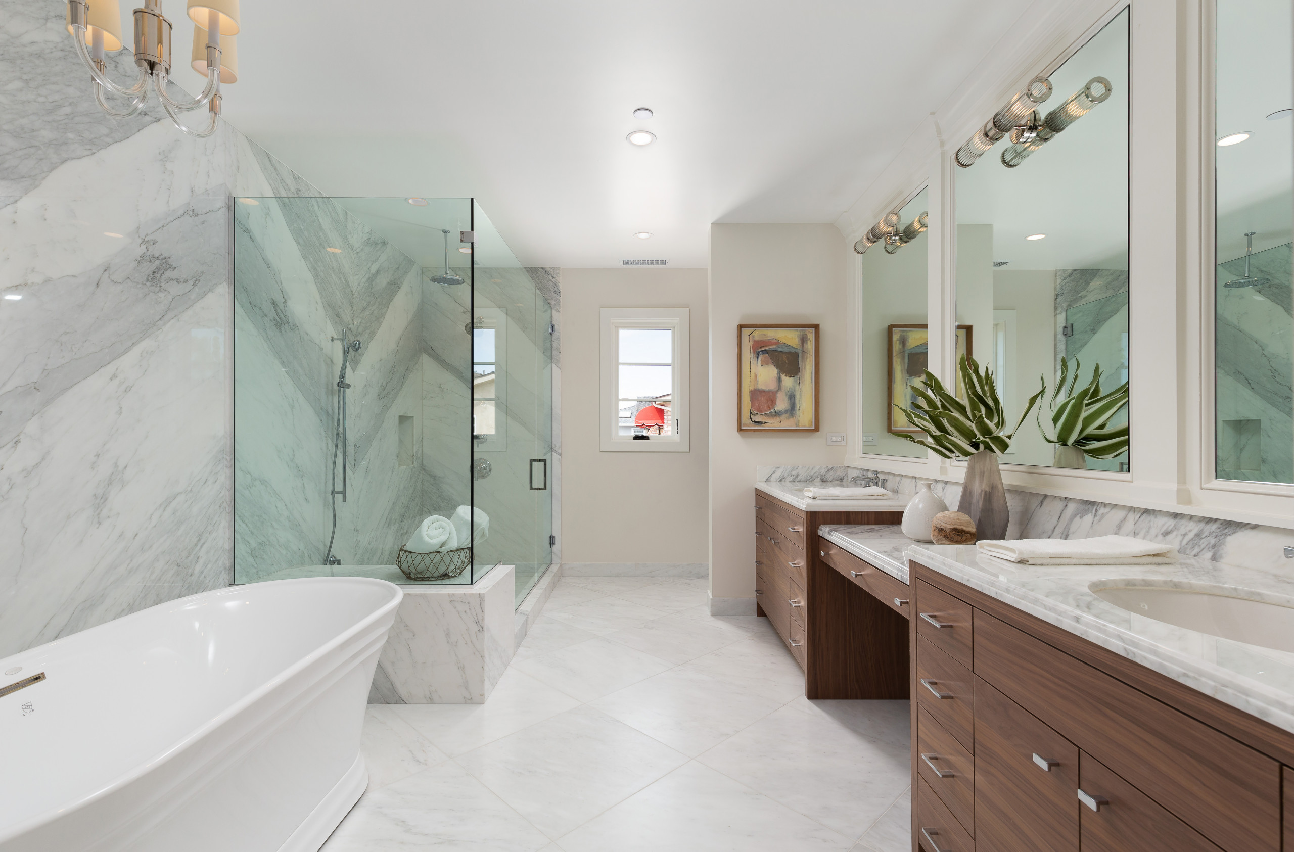 Luxury bathroom with marble walls, glass shower, and freestanding bathtub.
