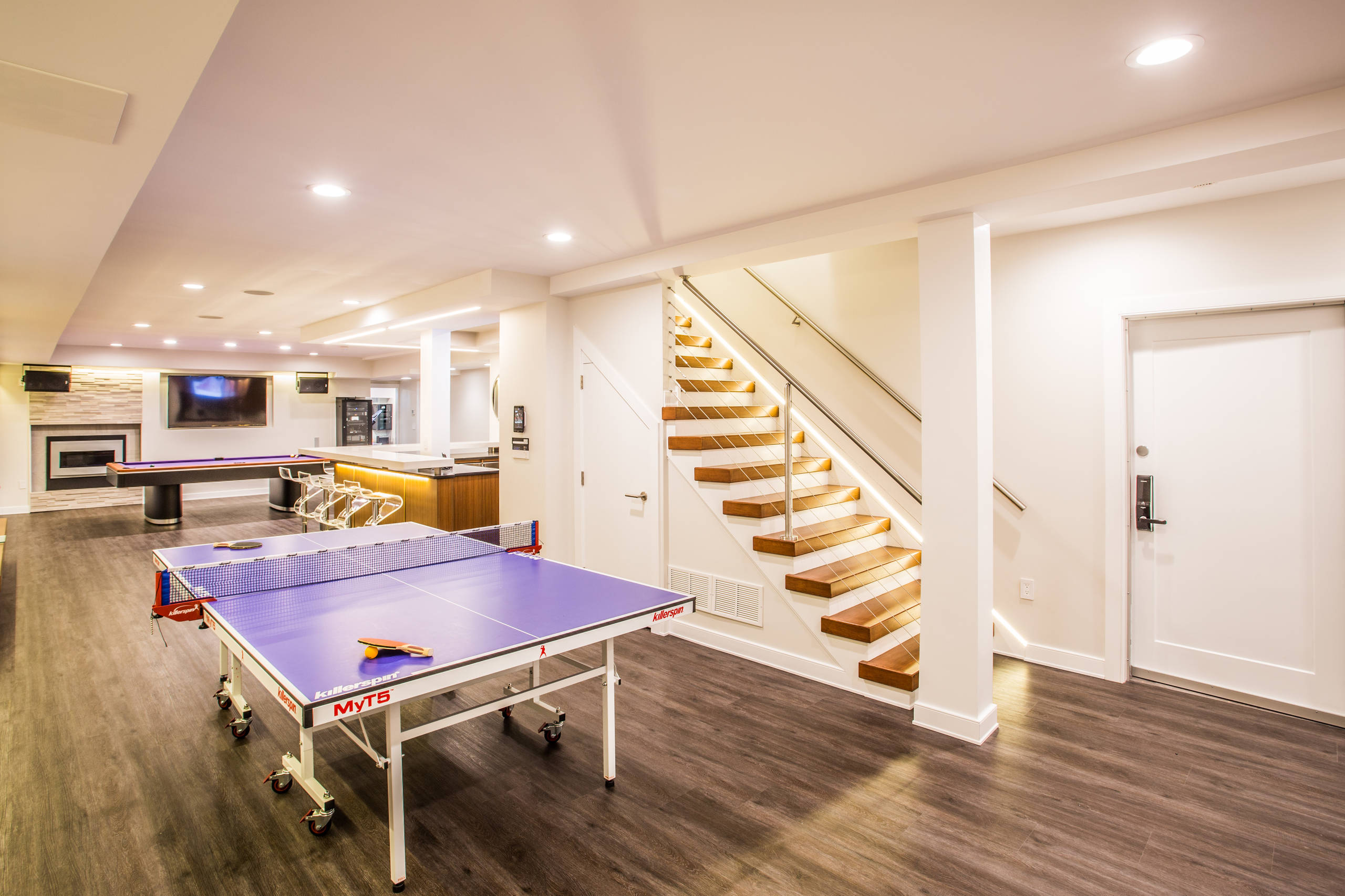 Modern basement with ping pong table, bar area, and entertainment zone.