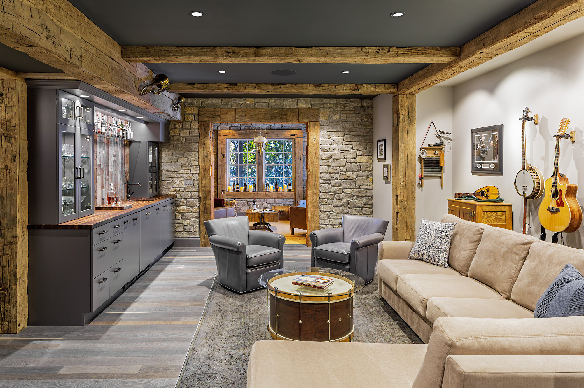 Cozy rustic living room with stone walls, wood beams, and musical instruments on display.