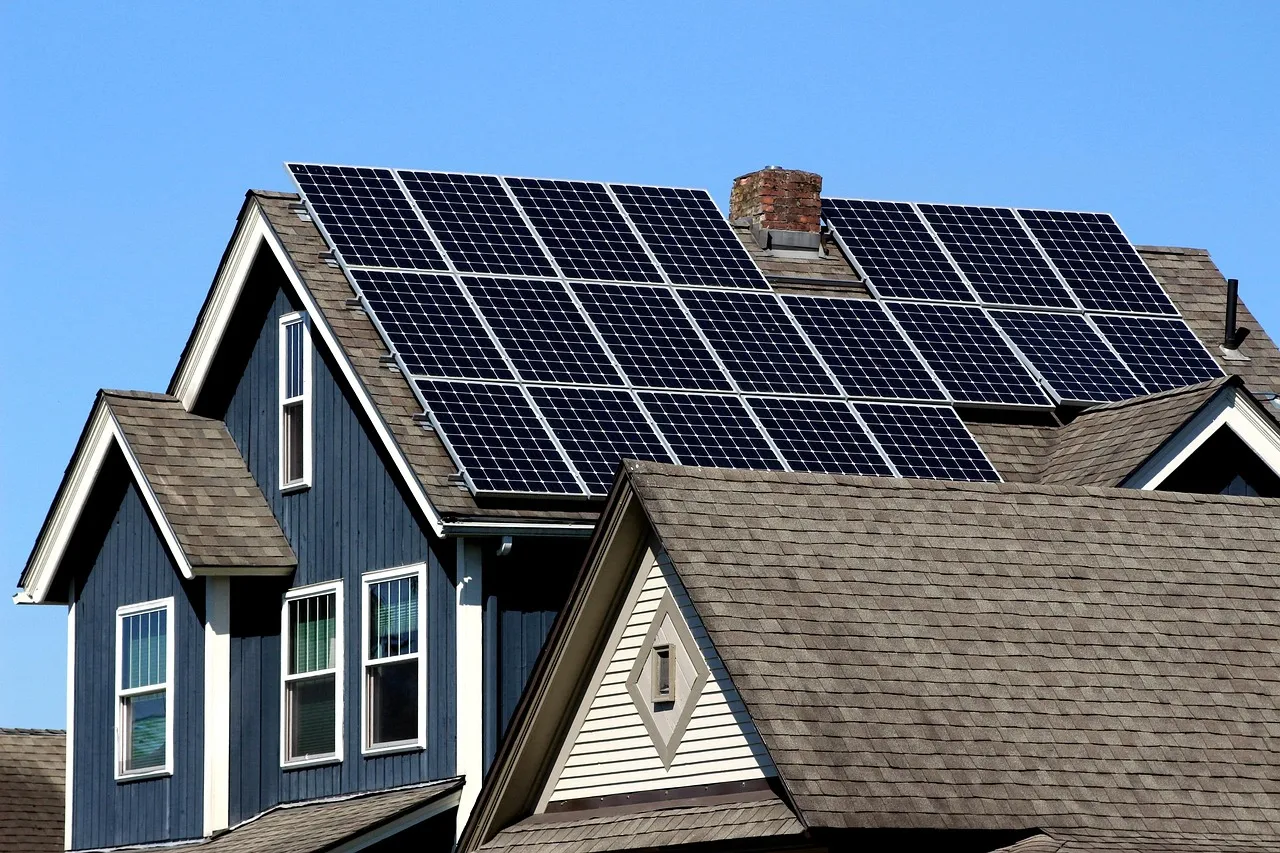 Residential home with rooftop solar panels installed on asphalt shingle roof under clear blue sky