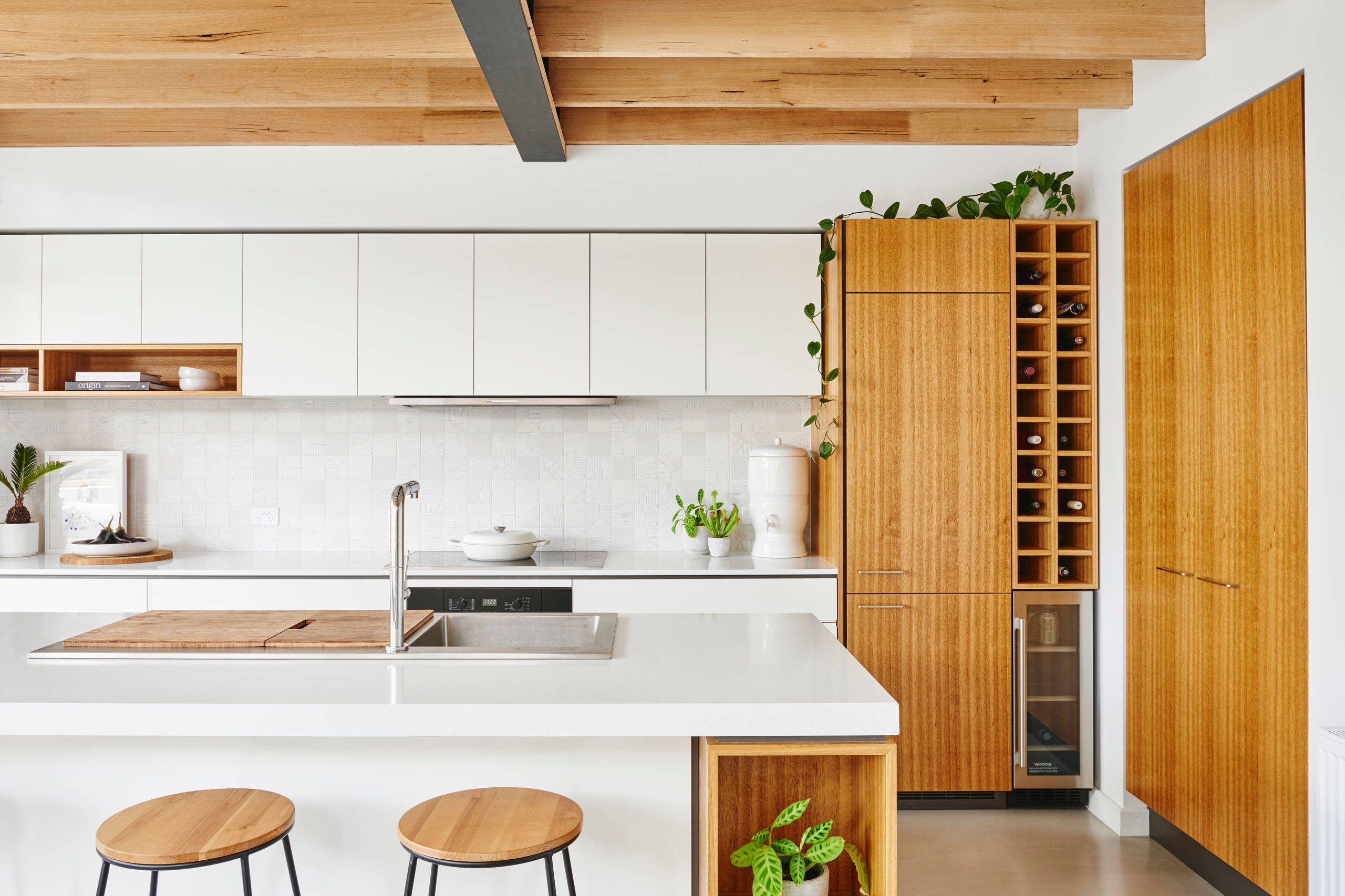 Minimalist white and wood kitchen with exposed ceiling beams and wine storage