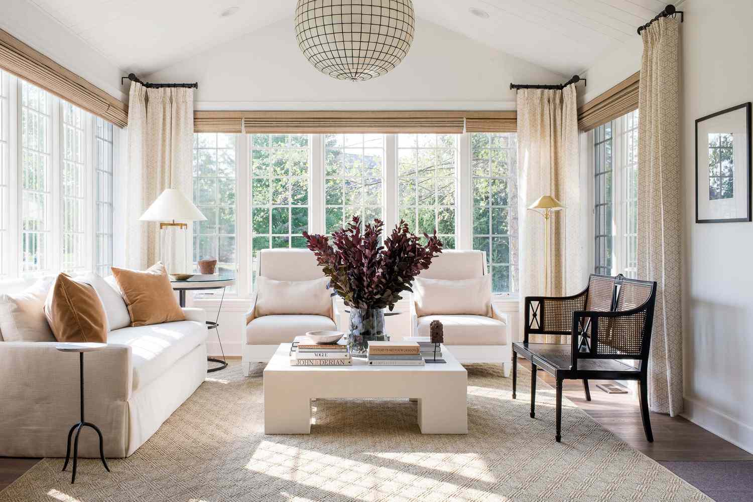 Bright sunroom with floor-to-ceiling windows, neutral furnishings, and modern decor