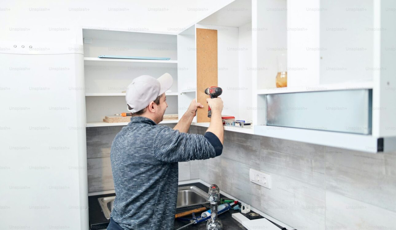 Kitchen remodeling expert installing upper cabinet shelves with a power drill