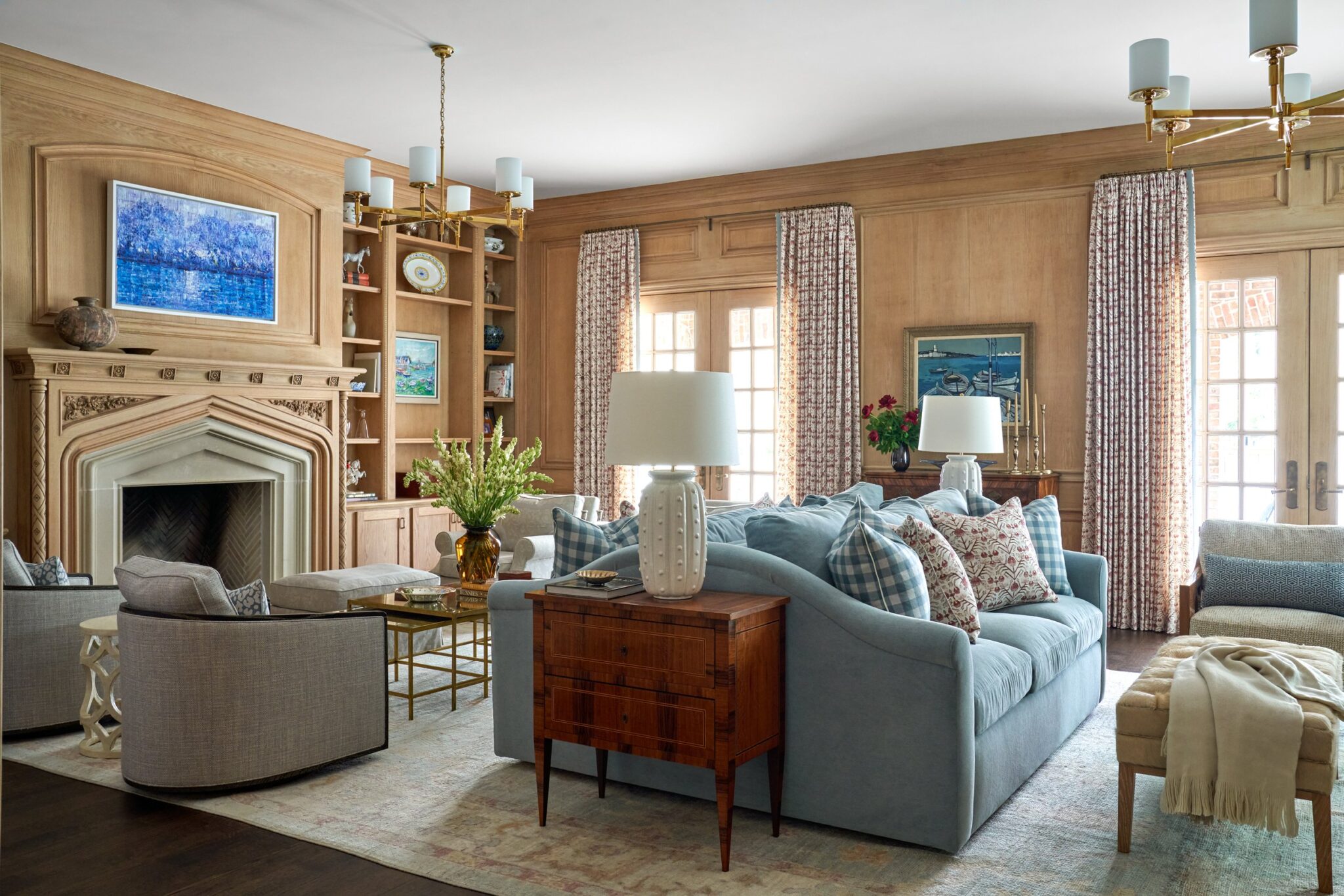 Elegant traditional living room with wood-paneled walls, blue sofa, fireplace, and classic decor.