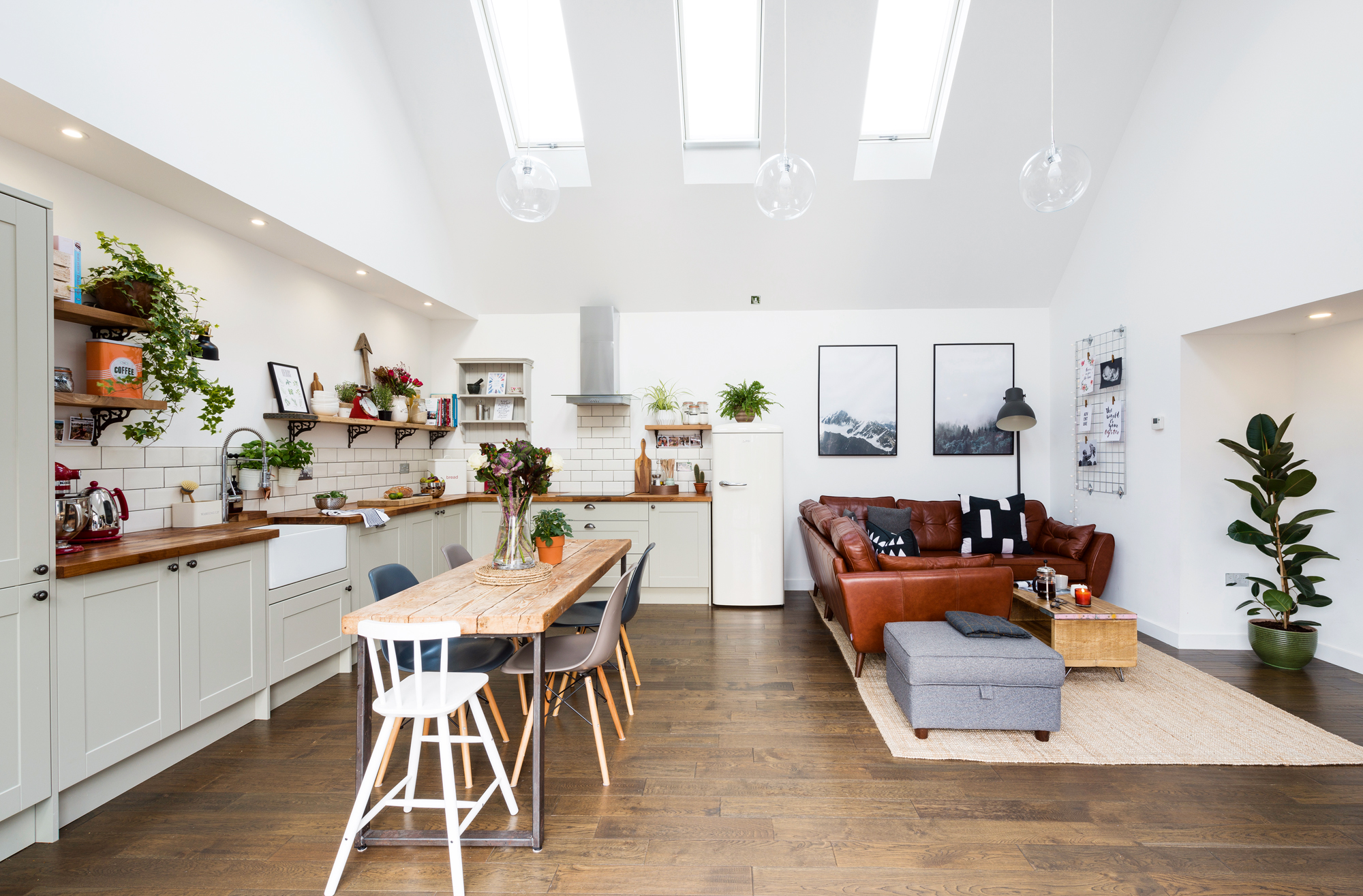 Open-plan kitchen and living room with skylights, wooden floors, and a mix of modern and rustic decor.