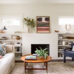 Cozy modern living room with neutral tones, mid-century furniture, and built-in shelving.