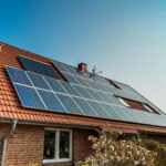 Brick house with red tile roof equipped with solar panels under a clear blue sky