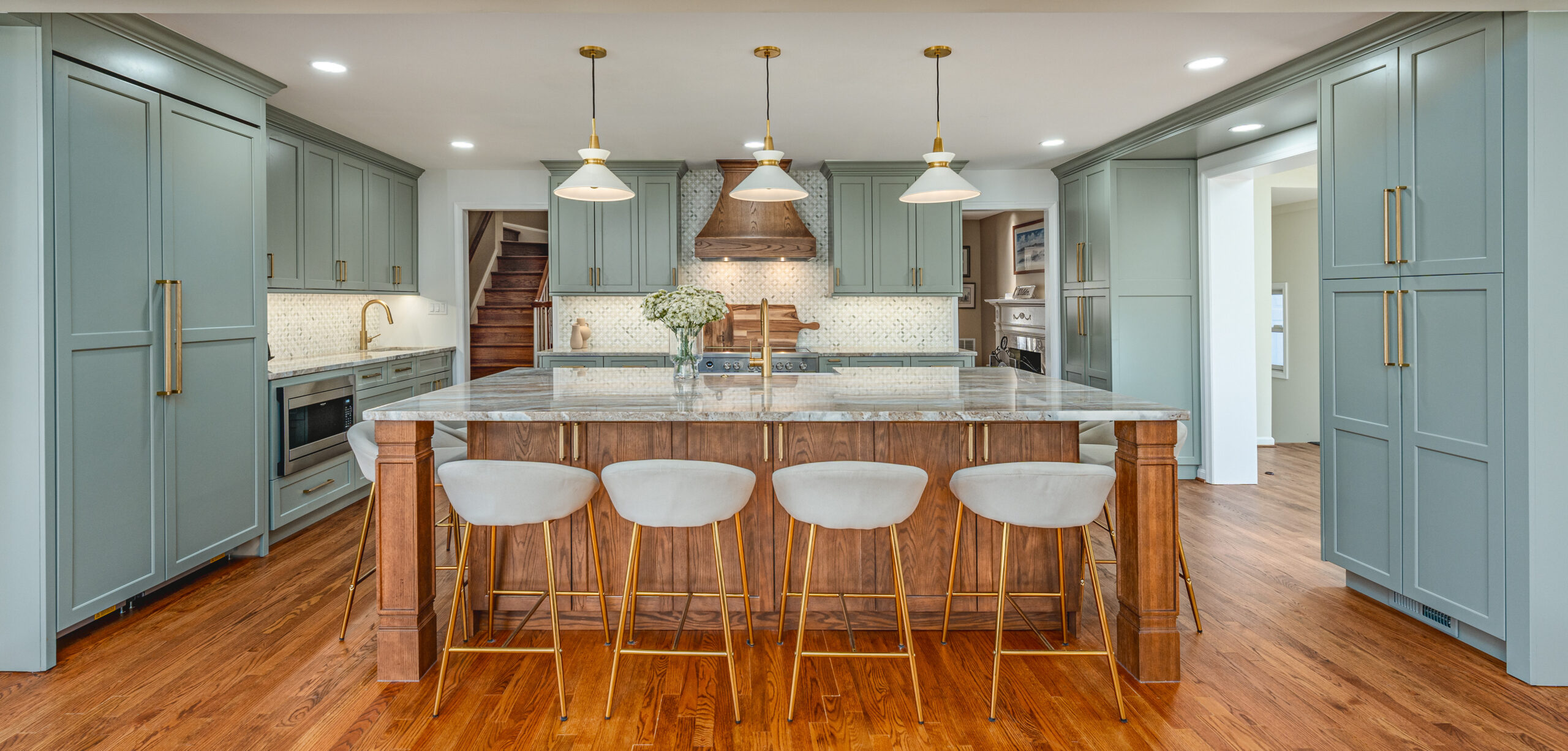 Custom sage green shaker kitchen with large wood island, quartz countertop, and brass fixtures by Fineline Kitchens, Vienna VA